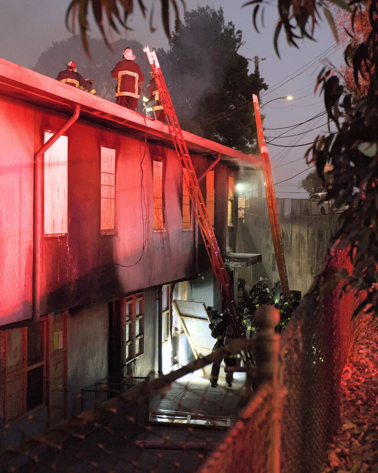 Sep 30th, 2024: Several San Francisco fire fighters dismantle a barricaded doorway while others stand on the rooftop.