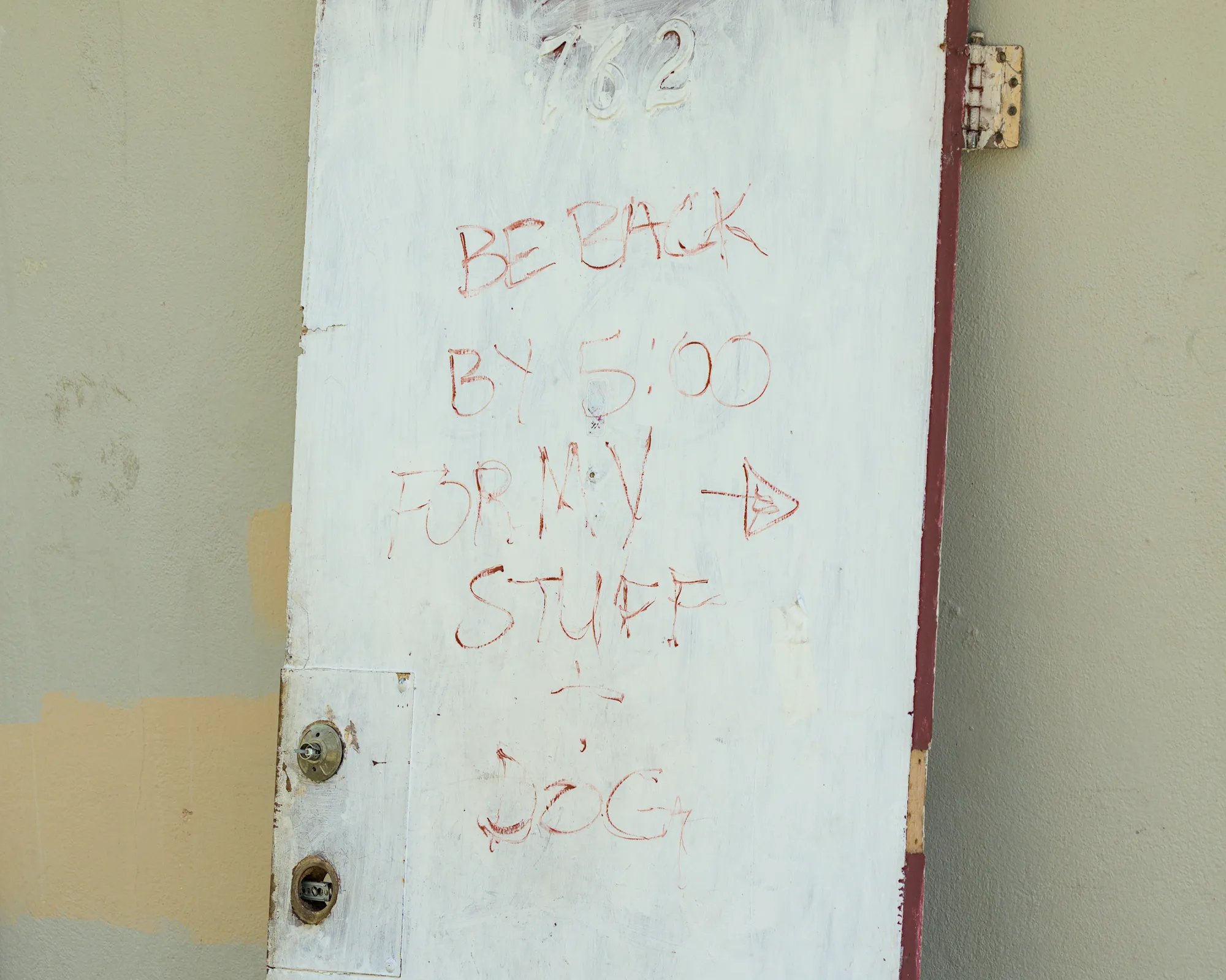 Apr 27th, 2026: A door leans against a building with the message 'BE BACK BY 5:00 FOR MY STUFF + DOG'.